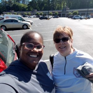 2 women, 1 african american and 1 white in parking lot after a run