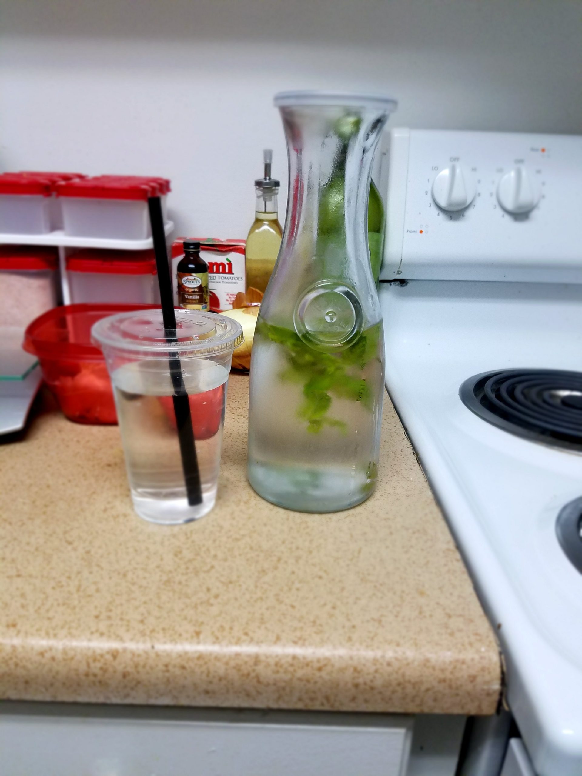 plastic lidded cup & water with mont in a glass carafe on counter